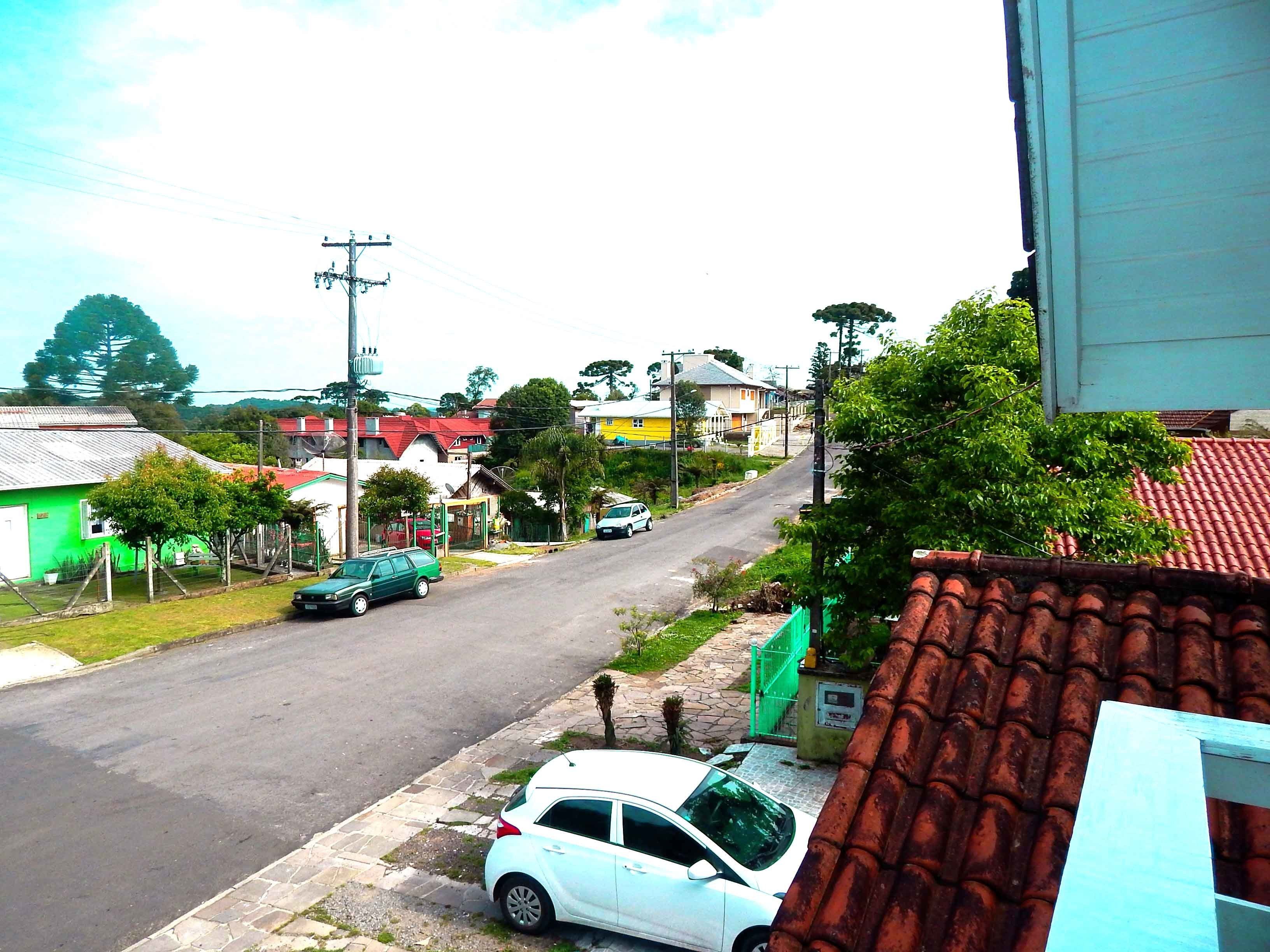 A residential street with houses, parked cars, and a clear sky.