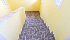 A stairway with stone steps and yellow walls, leading to a window.