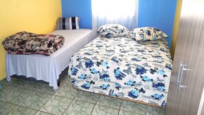 A bedroom with two beds, one with a floral bedspread and the other with a striped blanket.