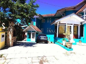 A two-story building with a blue facade, a small porch, and a car parked in front. - Lake Apartament Gran Familia (Canela)