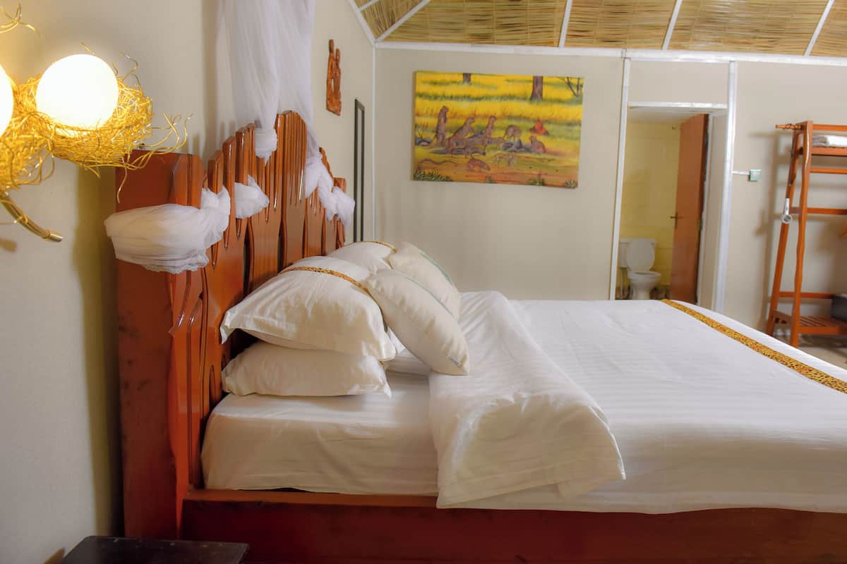 A bed with white bedding and a wooden headboard, a painting on the wall, and a ladder against the wall.