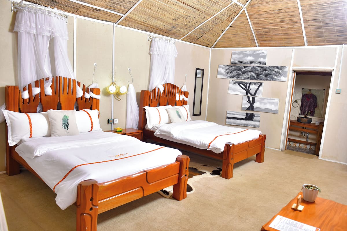 A room with two wooden beds, white bedding, a cowhide rug, a wooden nightstand, and a wall-mounted mirror.