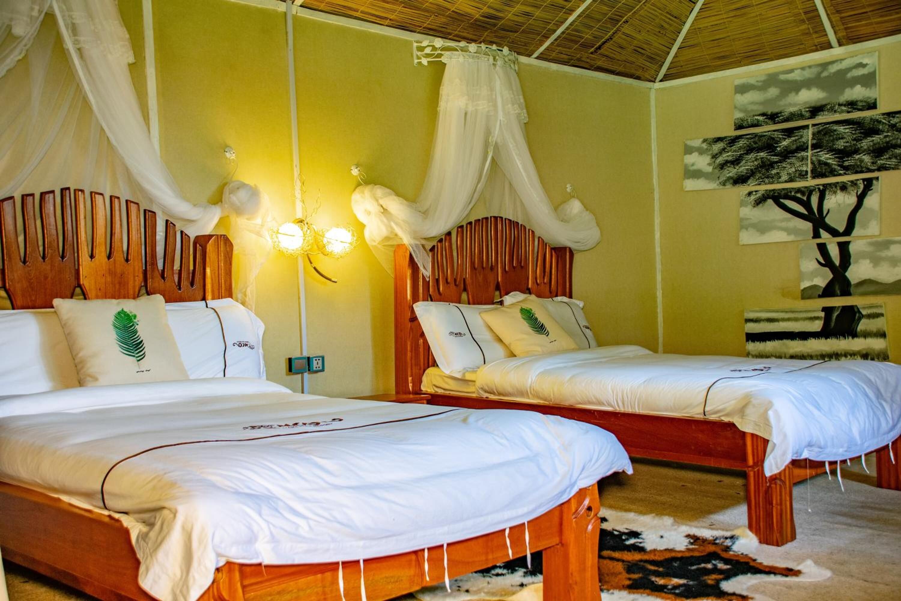 A room with two wooden beds, white bedding, and a canopy bed.