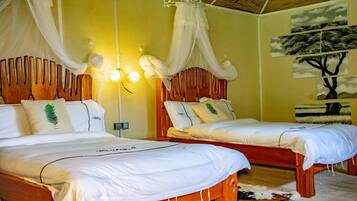A room with two wooden beds, white bedding, and a canopy bed.