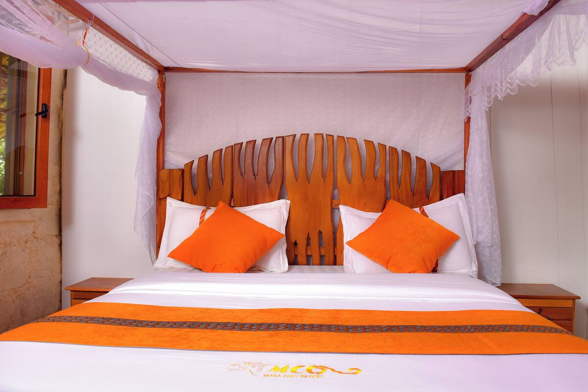 A bed with a canopy, two pillows, and a bedspread.