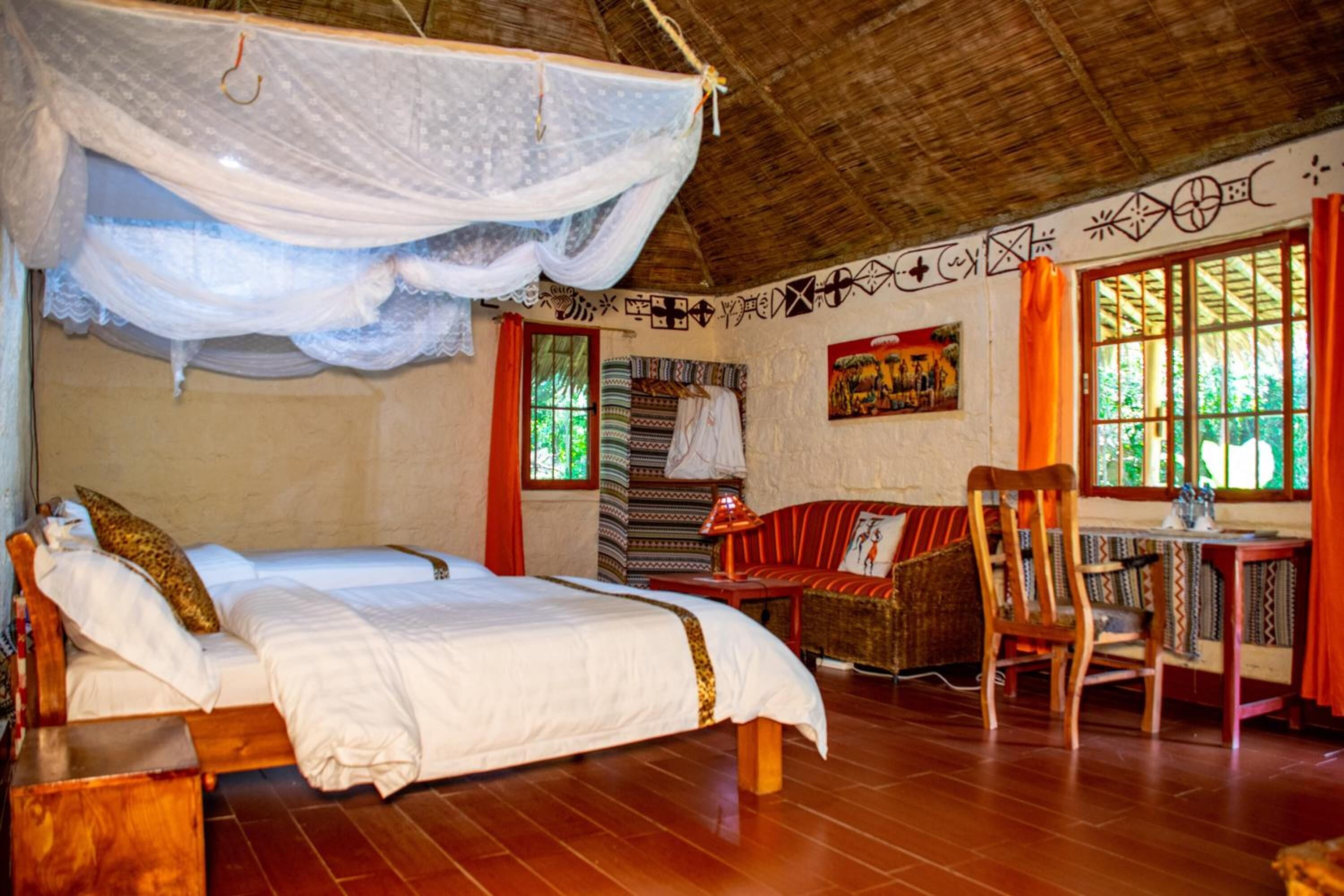 Una habitación con cama, una silla, una mesa y un ventanal con cortinas.