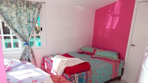 Een slaapkamer met een bed, een raam met gordijnen en een deur.