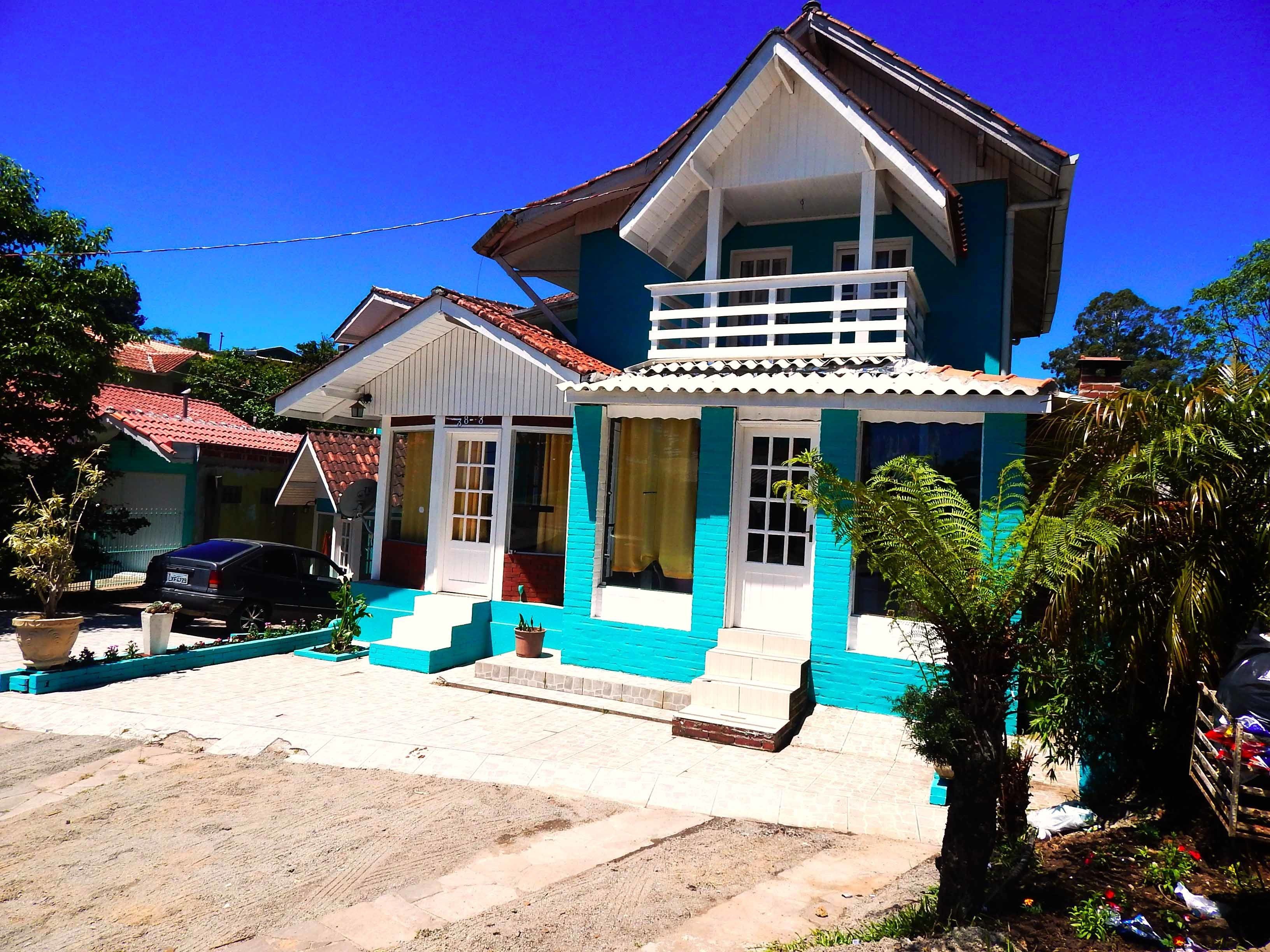 A two-story house with a balcony, a front porch, and a small garden area.