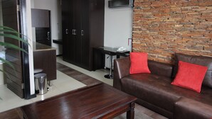 A modern living room with a brown leather sofa, a wooden coffee table, and a stone wall. - Alcazaba Lodges (Johannesburg)