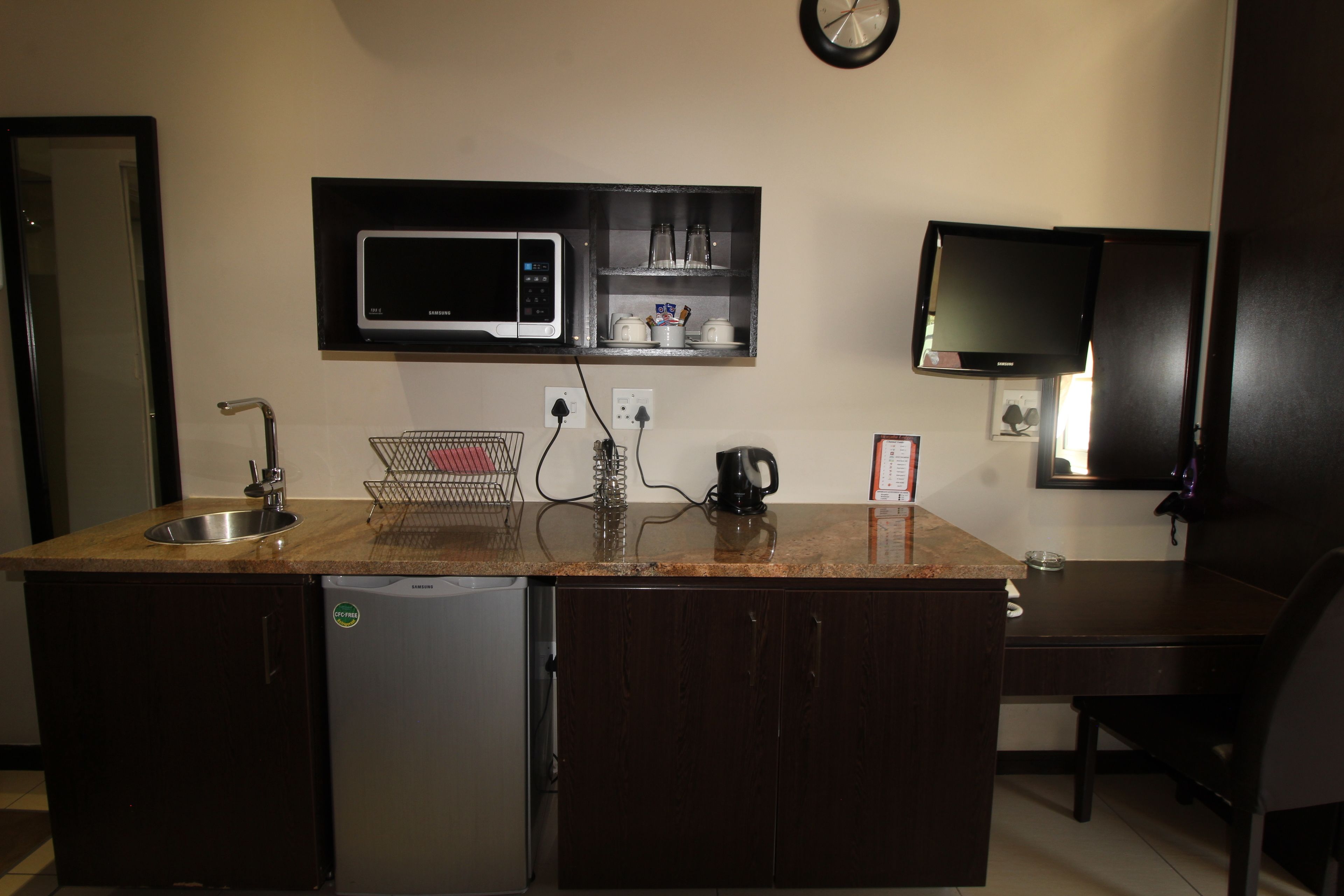 A compact kitchen with a microwave, sink, and a small refrigerator.