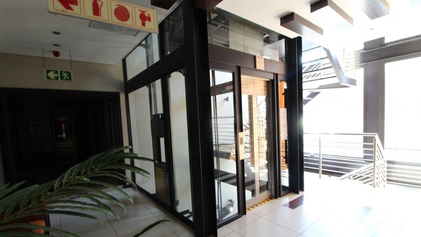 A modern interior with a glass door entrance, a staircase, and a potted plant. - Alcazaba Lodges (Johannesburg)
