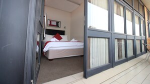 A hotel room with a bed, a window, and a door. - Alcazaba Lodges (Johannesburg)