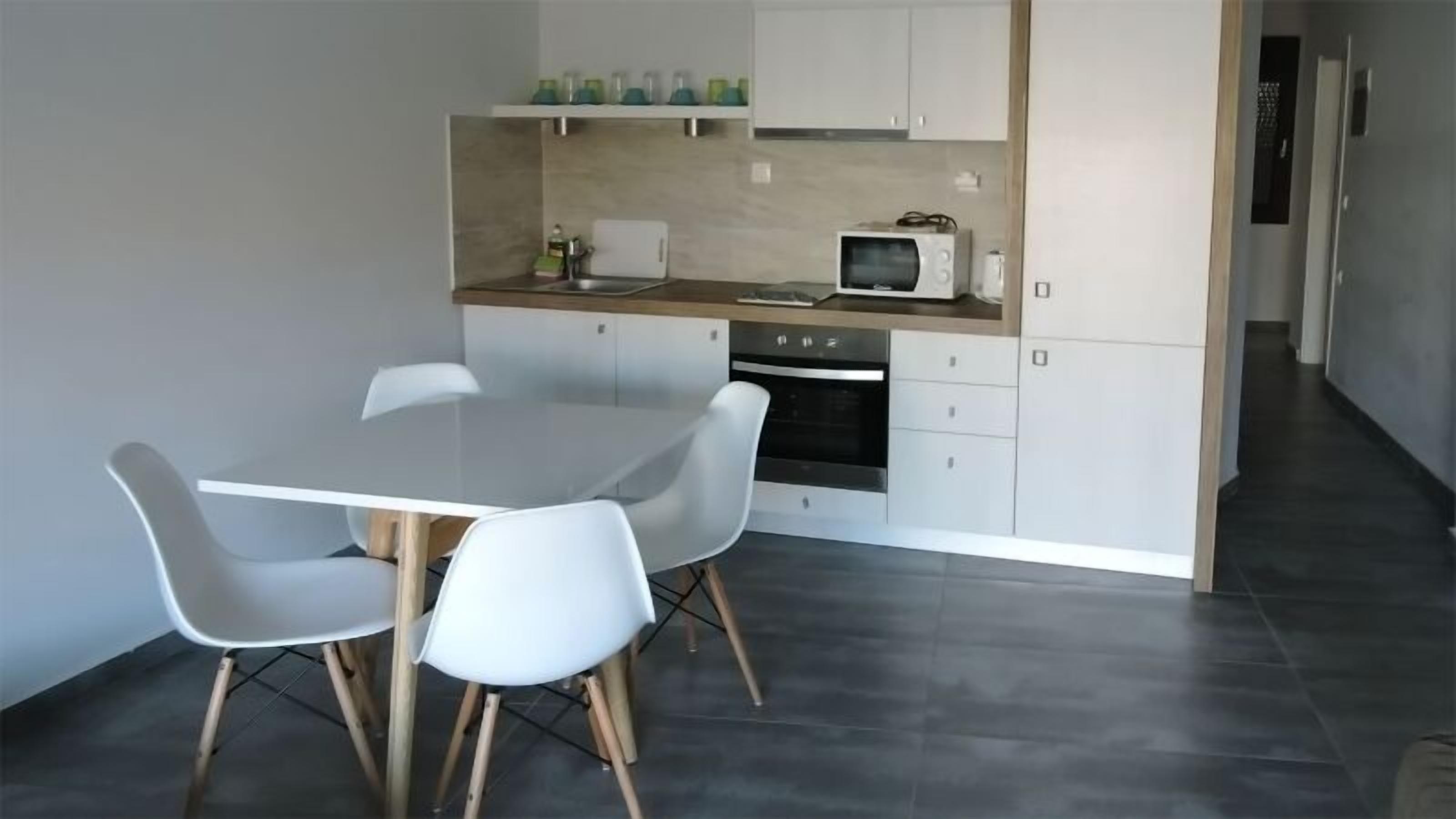 Una cocina moderna con armarios blancos, microondas y una mesa de comedor con cuatro sillas.