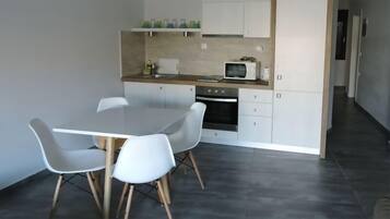 Una cocina moderna con armarios blancos, microondas y una mesa de comedor con cuatro sillas.