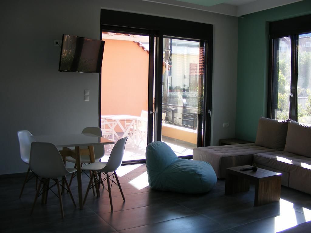 A modern living room with a sofa, a bean bag, and a dining table with chairs. There is a sliding glass door leading to an outdoor area.