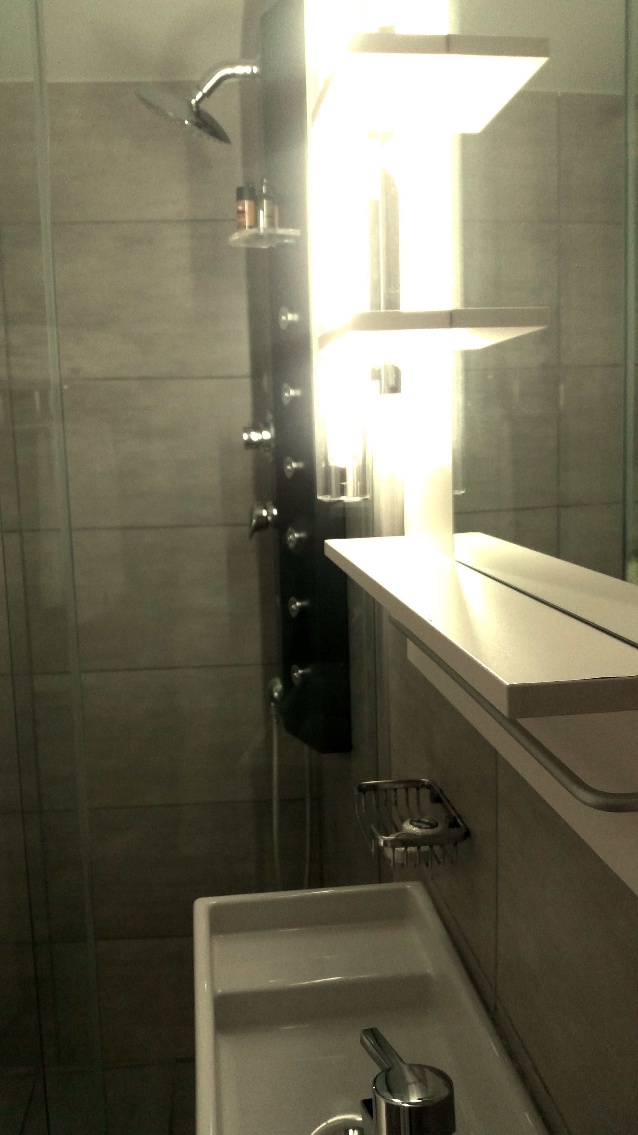 A bathroom with a shower, a sink, and a mirror.