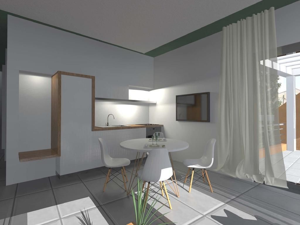 A modern dining area with a round table and four chairs, a kitchen area with a countertop and cabinets, and a large window with sheer curtains.