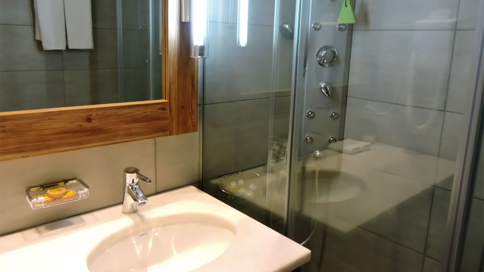 A bathroom with a white sink, a mirror, and a glass shower enclosure.