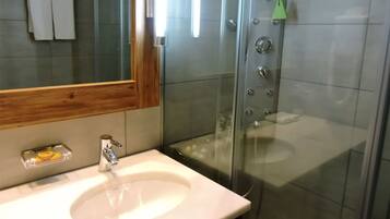 A bathroom with a white sink, a mirror, and a glass shower enclosure.