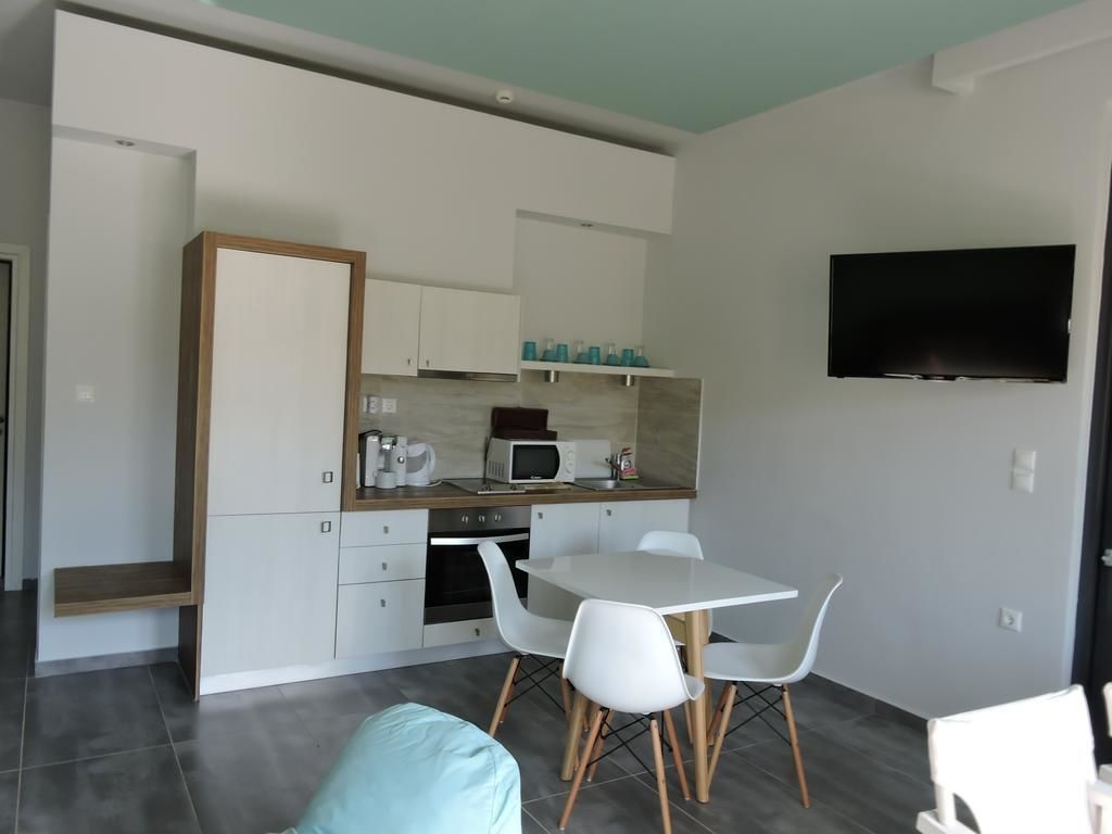 A modern kitchen with white cabinets, a microwave, and a coffee maker. There is a dining table with white chairs.