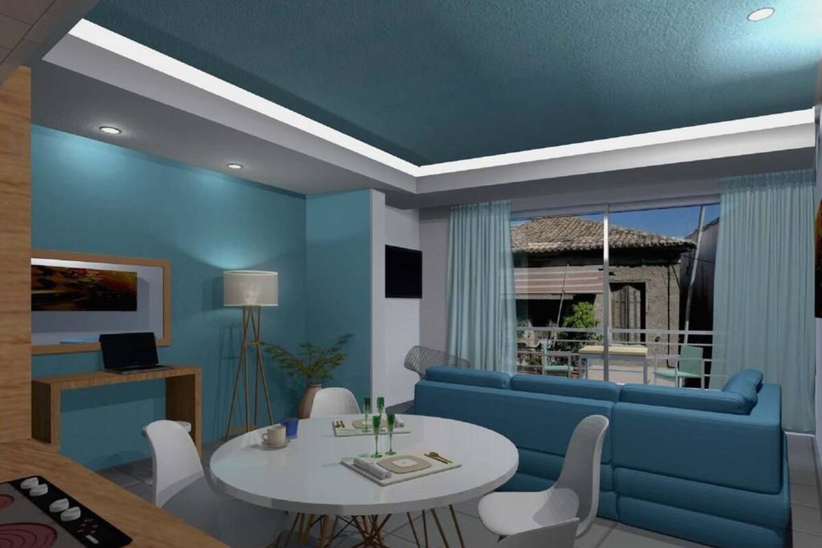 A modern living room with a round dining table, blue sofa, and a view of the outside.