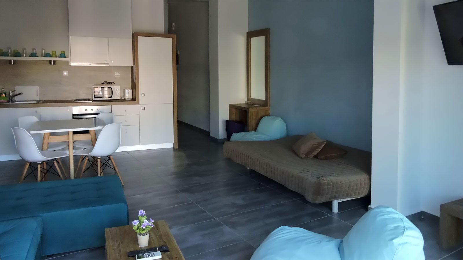 A modern living room with a sofa, a coffee table with a vase, and a dining area with a table and chairs.
