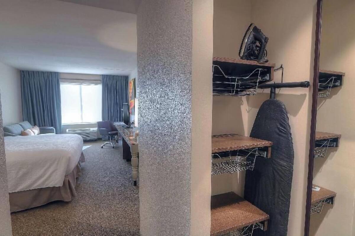A hotel room with a bed, a desk, a chair, and a small seating area.