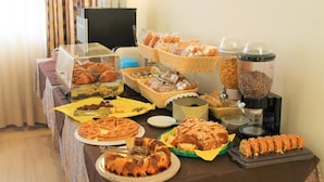 A buffet table with various baked goods, including pastries, bread, and a cake, along with coffee and tea options. - Hotel Santa Lucia (Bastia Umbra)