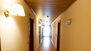 A long, narrow hallway with wooden floors and walls, featuring doors and wall-mounted light fixtures. - Hotel Santa Lucia (Bastia Umbra)
