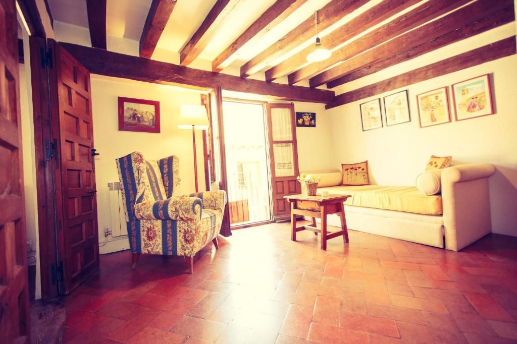 A room with a wooden ceiling, a sofa, a chair, and a table.