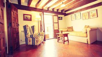 A room with a wooden ceiling, a sofa, a chair, and a table.