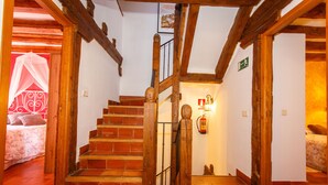 Un escalier en bois, avec un extincteur et une trousse de premiers secours fixés au mur.