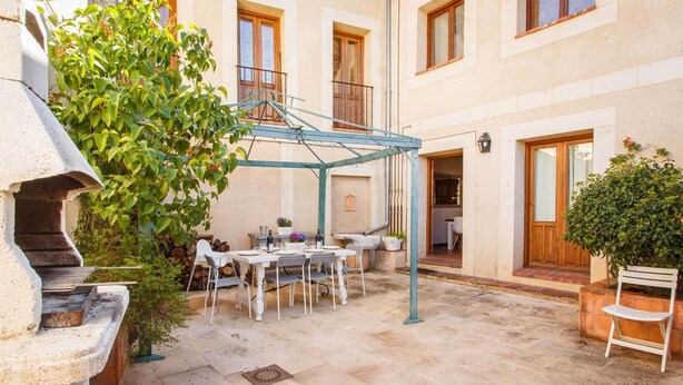 Une cour dotée d’un espace de restauration extérieur abrité, d’un barbecue en pierre et de plantes en pot.