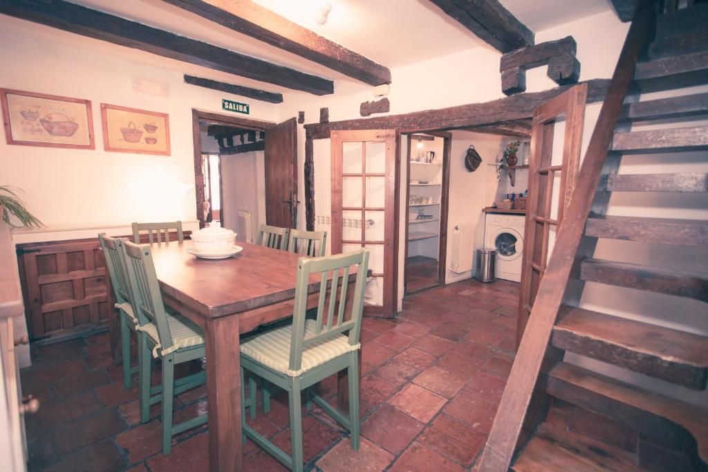 A rustic dining area with a wooden table and chairs, a staircase, and a laundry room.