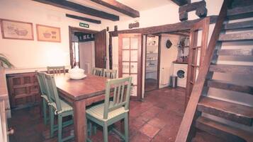 Un comedor rústico con una mesa y sillas de madera, una escalera y un cuarto de lavado.