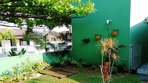 A small garden area with a wooden deck, potted plants, and a green wall. - Pousada Ares do Sul (Penha)