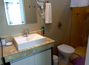 A bathroom with a sink, toilet, and shower. - Pousada Ares do Sul (Penha)