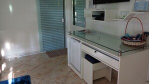 A modern room with a glass desk, a television mounted on the wall, and a sliding door. - Pousada Ares do Sul (Penha)