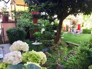A garden with a variety of plants and flowers, a small table with chairs, and a bench. - Lori's Inn (Mondovi)