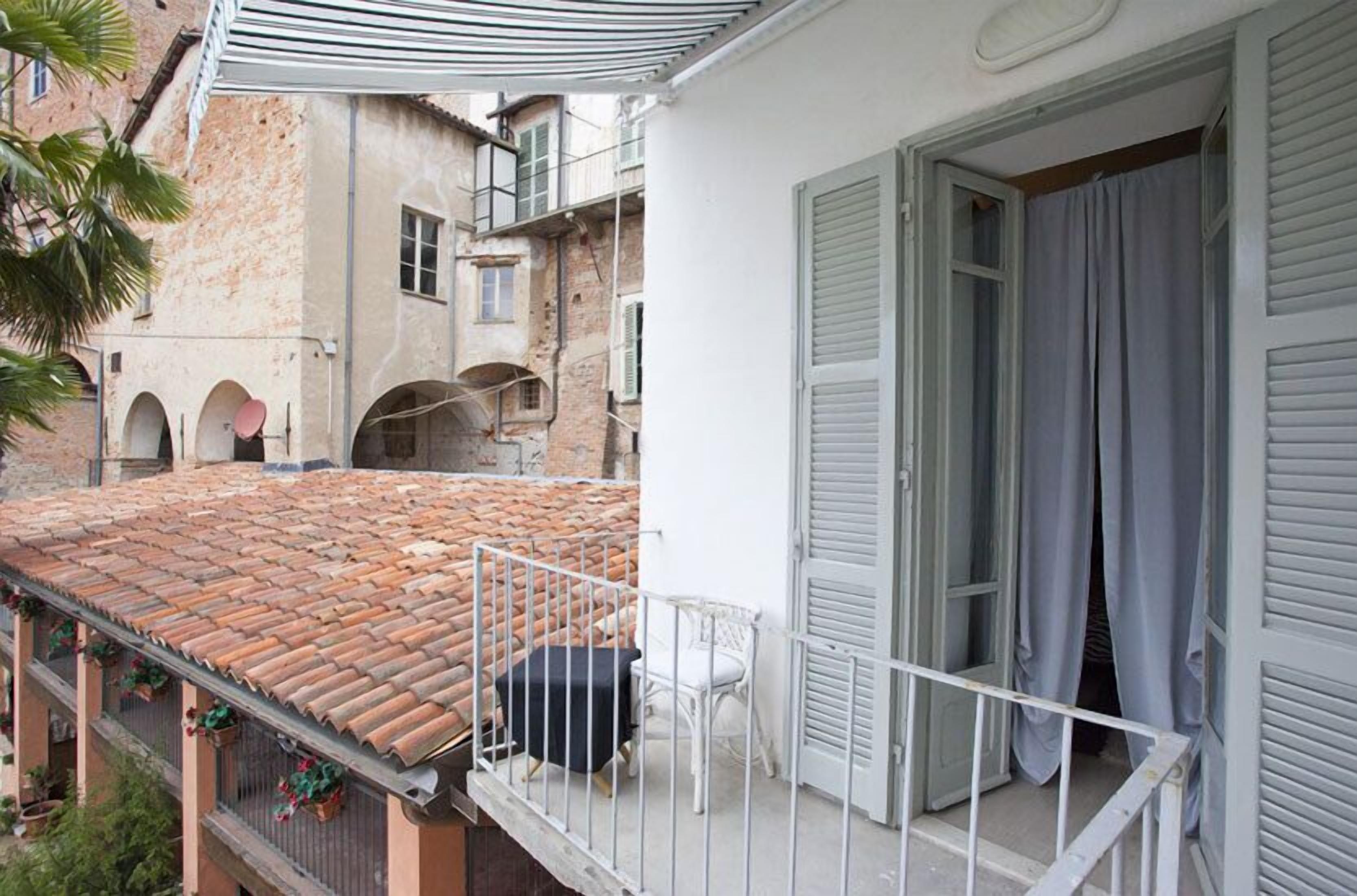 A balcony with a tiled roof, a white chair, and a table.