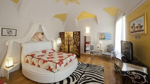 A bedroom with a round bed, a zebra-patterned rug, a TV, and a sun-shaped ceiling decoration. - Lori's Inn (Mondovi)