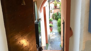 A narrow hallway with a wooden door, a small table with a chair, and a potted plant. - Lori's Inn (Mondovi)