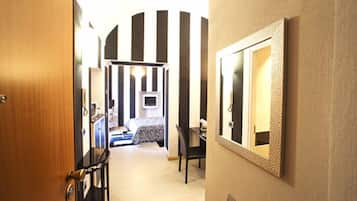 A hotel hallway with a bed, a desk, and a mirror on the wall.