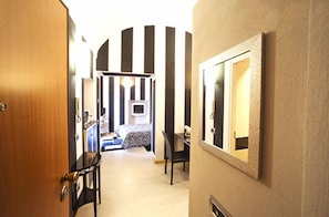A hotel hallway with a bed, a desk, and a mirror on the wall. - Lori's Inn (Mondovi)
