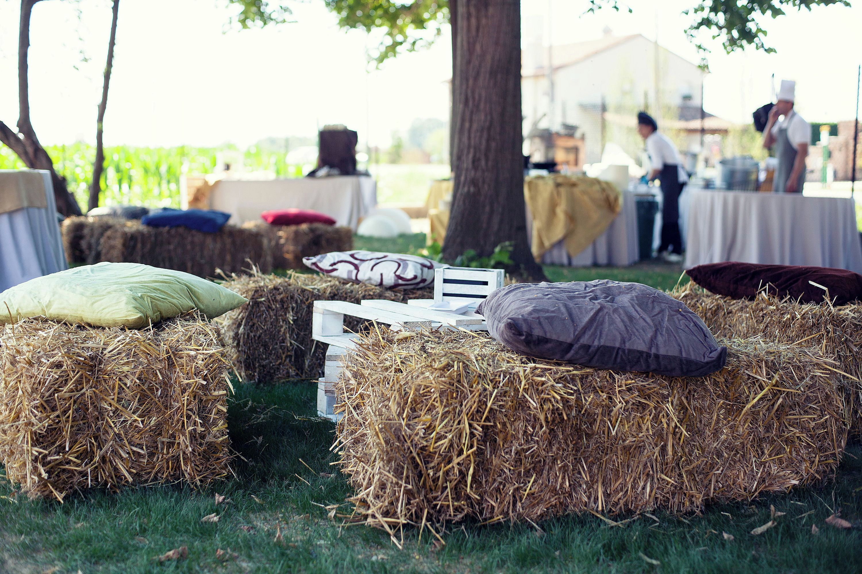 Heuballen mit Kissen auf einer Wiese, wahrscheinlich bei einer Outdoor-Veranstaltung oder einem Festival.