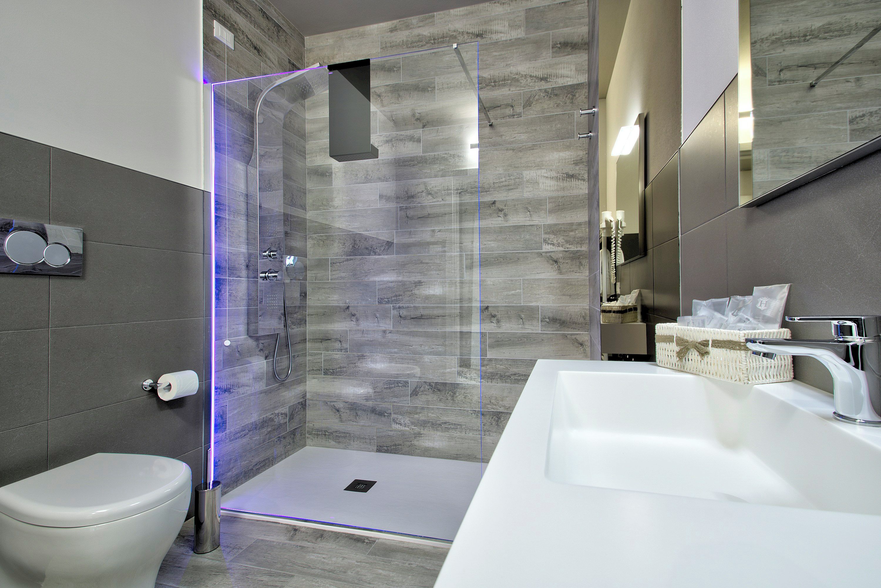 A modern bathroom with a glass-enclosed shower, a white sink, and a toilet.