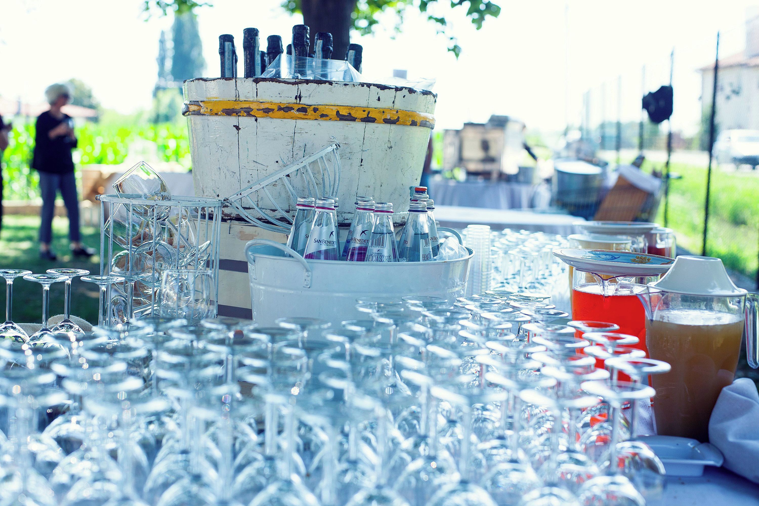 A table with numerous empty wine glasses and a large ice bucket with bottles.