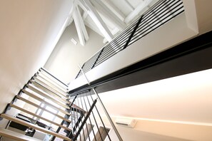 Una escalera moderna con barandillas metálicas y una pared blanca.