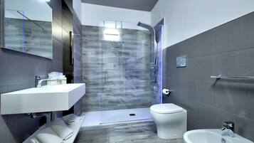 A modern bathroom with a glass-enclosed shower, a white sink, and a bidet.