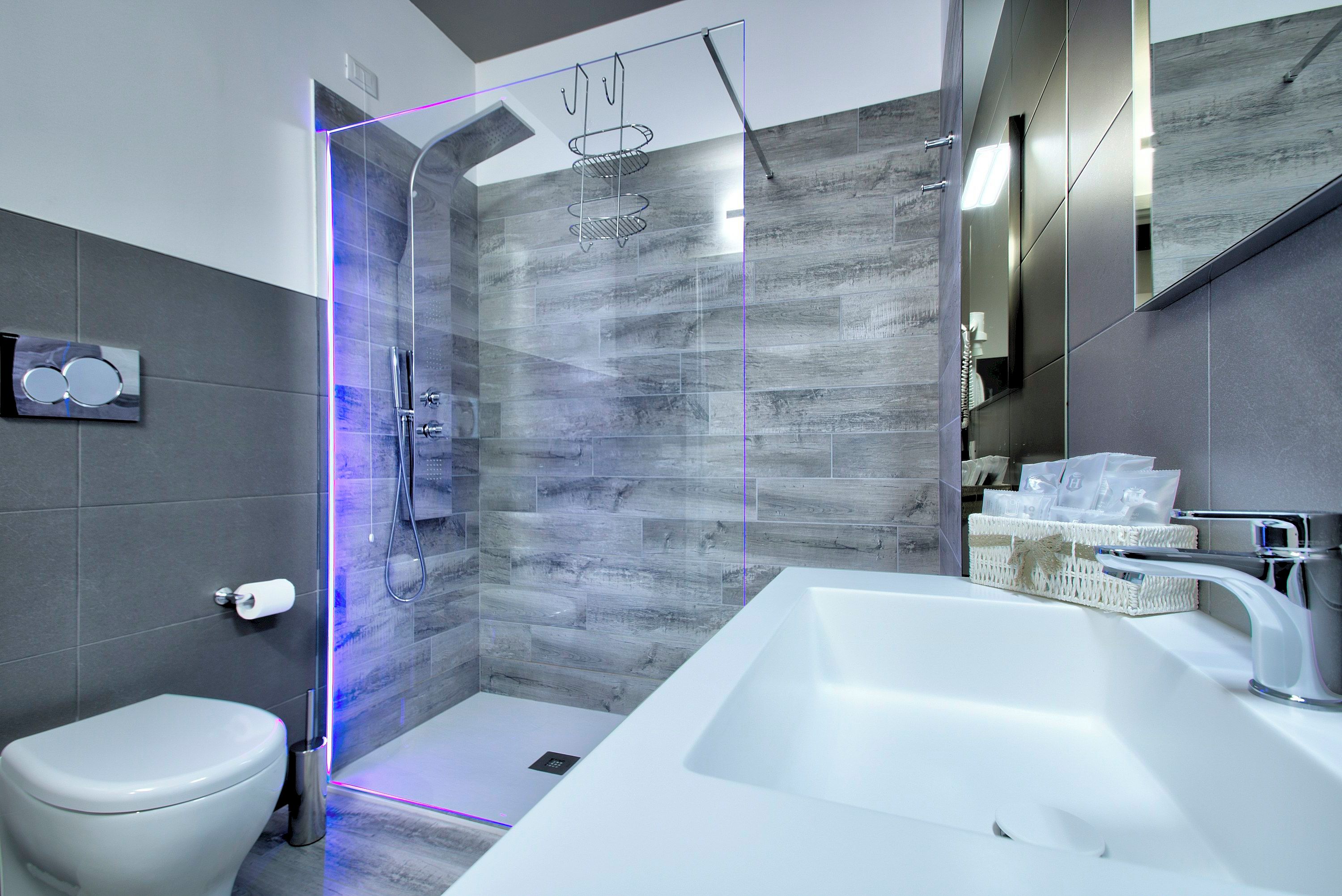 Une salle de bain moderne avec une douche à parois de verre, un lavabo blanc et des toilettes.